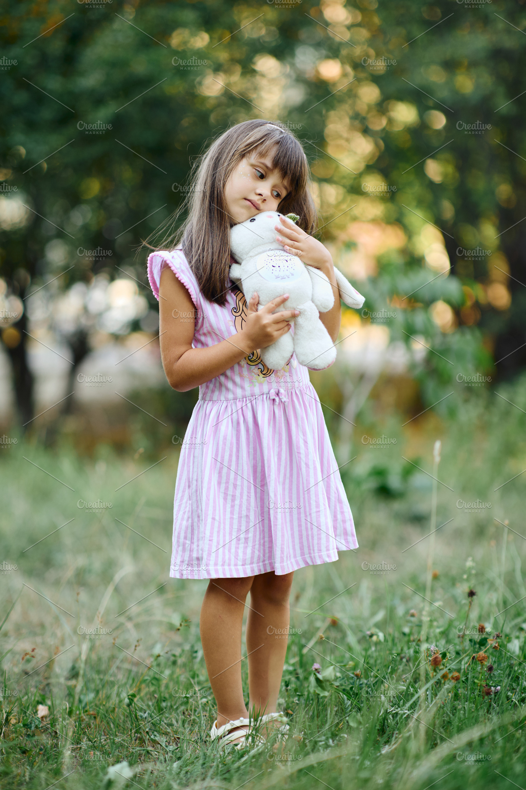 Cute little girl hugging plush toy bunny in summer park., a Person Photo by Rohan Photography