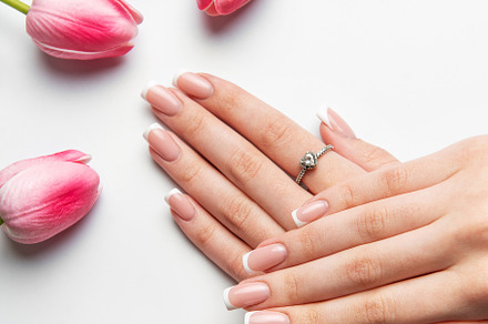 Woman showing french manicure near pink tulips on white backgrou