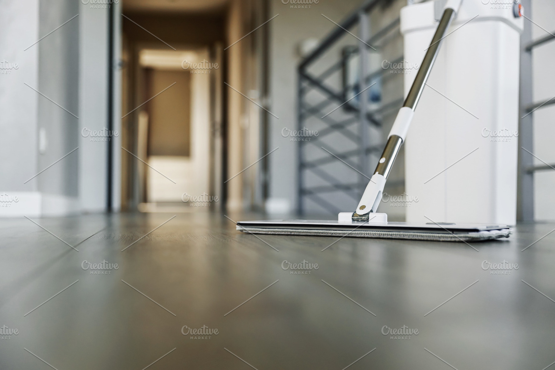 Cleaning supplies: mop and bucket with wringer on wooden laminate floor, a Business Photo by Lenor4ik