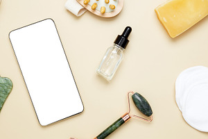 Smartphone mockup surrounded by skincare items: marble face roller, gua sha too, a Photo by matucha