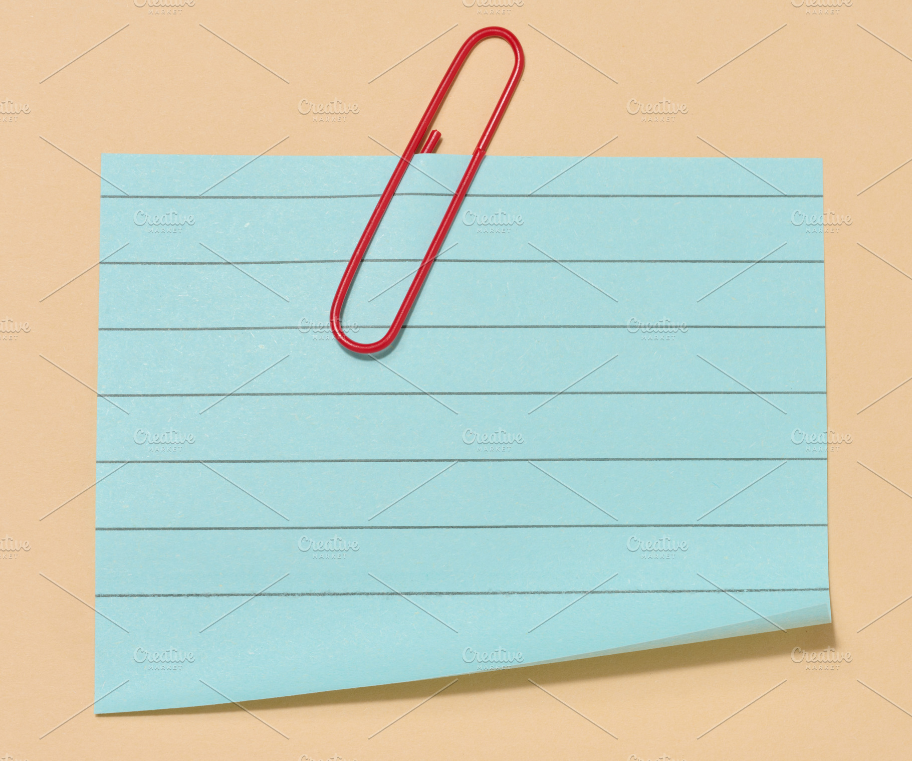 Blue sticky note with a red paper clip attached to it, placed on, a Business Photo by ndanko