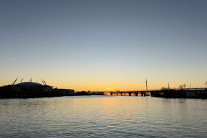 A serene sunset over a river, with silhouettes of buildings and a bridge in the, a Nature Photo by Textures & Backgrounds