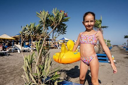Happy girl in colorful swimsuit holding inflatable duck at sunny beach, a Photo by AS photostudio