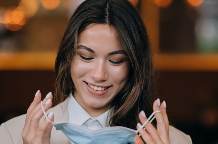 Girl in takes off her protective medical face mask