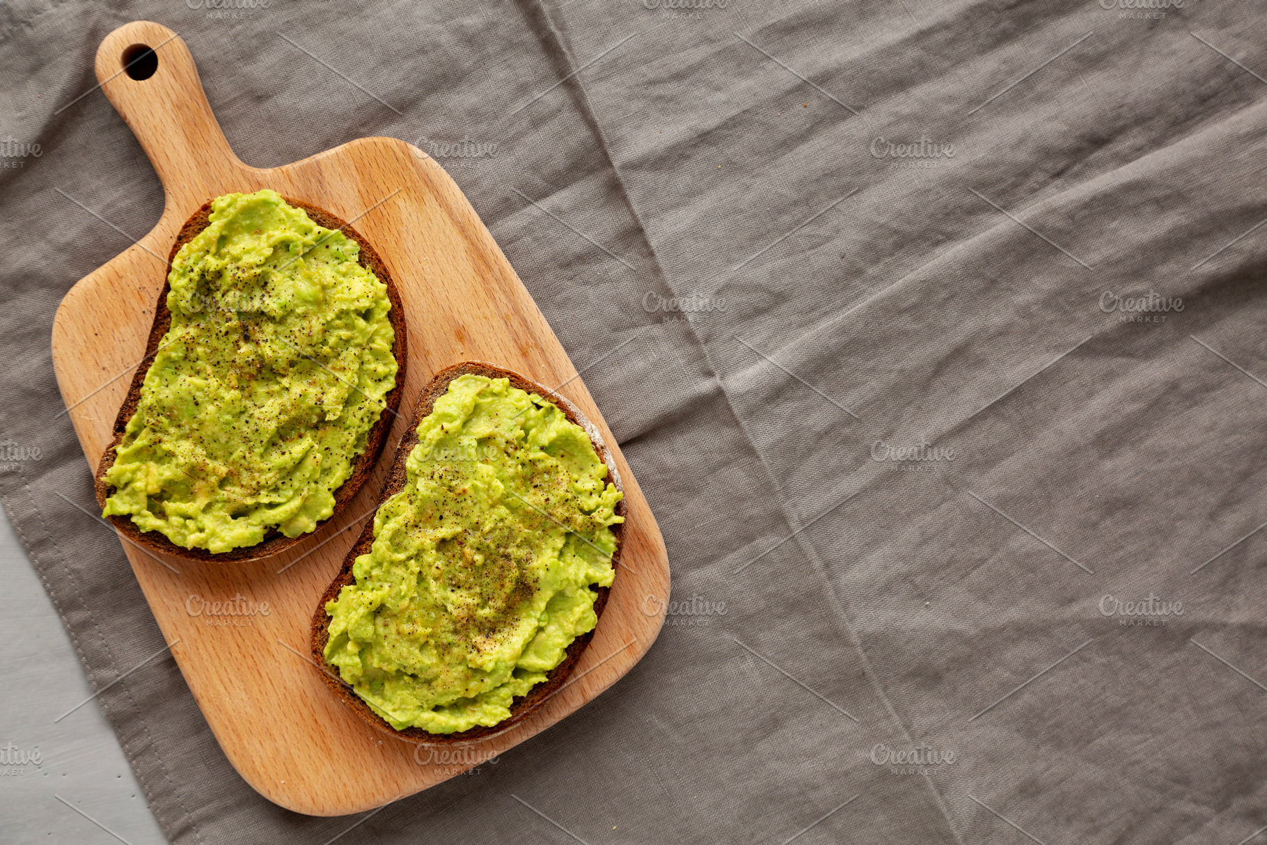 Homemade Avocado Toast with Salt and Pepper on a wooden board, t, a Food & Drink Photo by LiudmylaChuhunova
