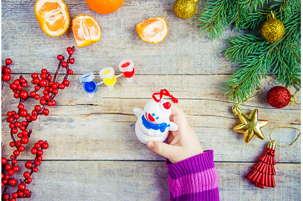 A child paints a Christmas toy, a, a Holiday Photo by yanadjana
