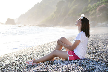 Young woman sitting at pebble beach, a Person Photo by Foxys