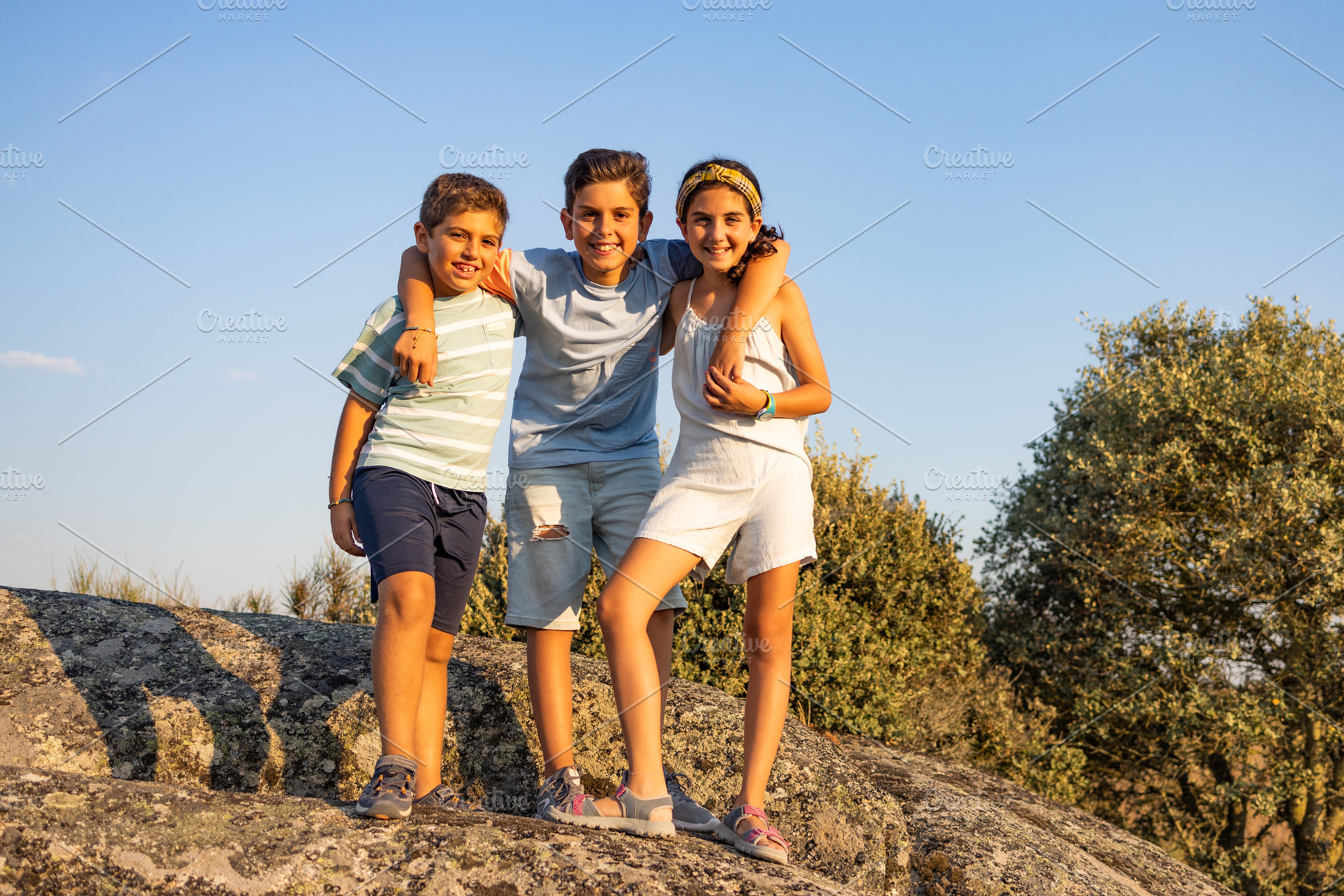 Three kids on a top of a rock on their summer vacation, a Person Photo by Cosca