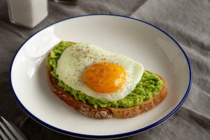 Homemade Avocado Toast with Egg on a Plate, side view., a Food & Drink Photo by LiudmylaChuhunova