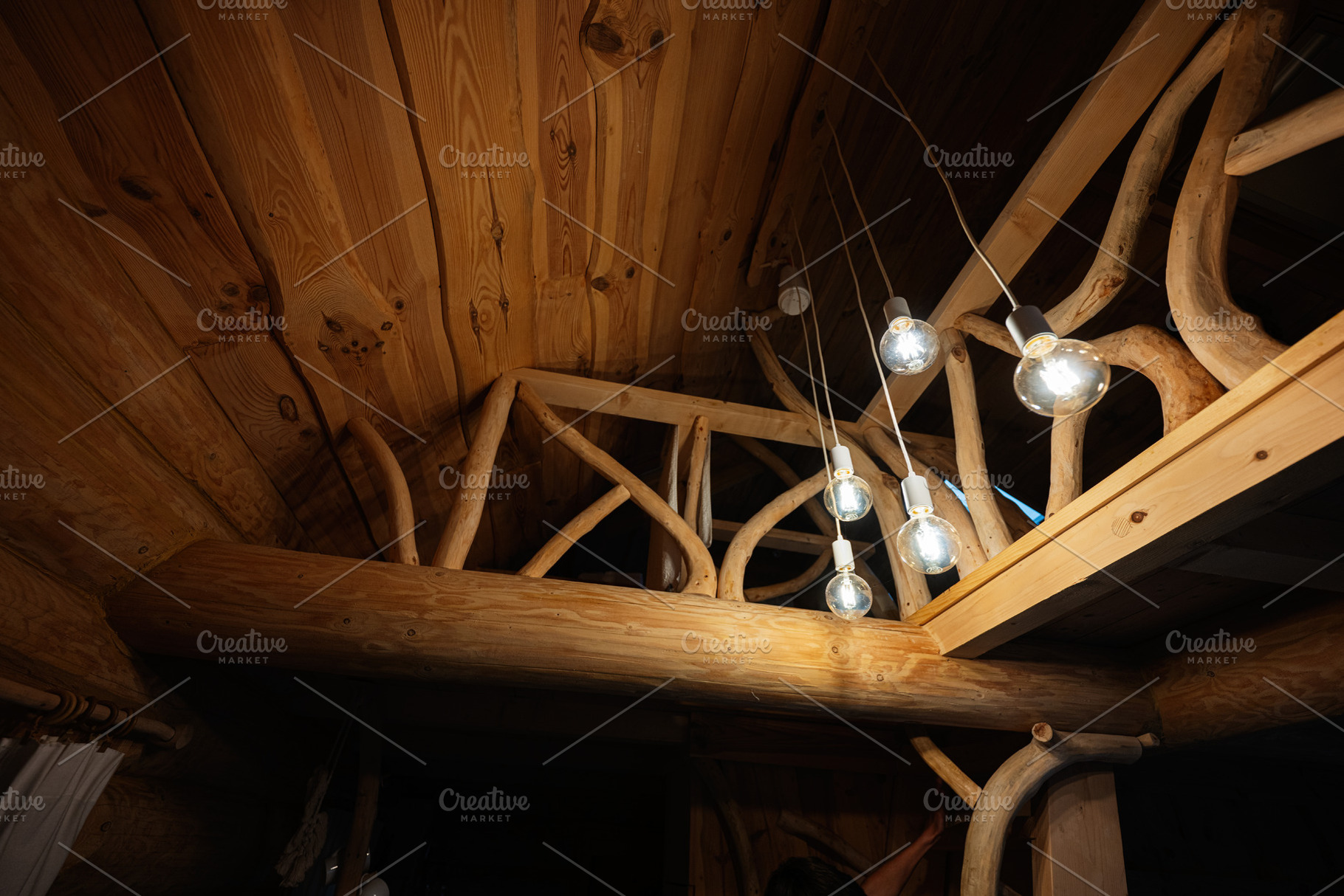 Rustic interior with wooden balustrade and glowing suspended lightbulbs, a Photo by AS photostudio