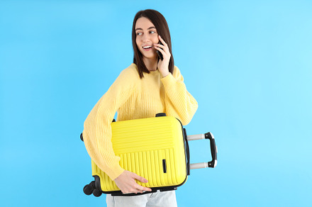 Attractive woman with phone and travel bag on blue background, a Person Photo by AtlasStudio PRO