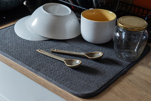 Clean washed dishes arranged on a gray drying mat on a kitchen c, an Industrial Photo by MDBildes