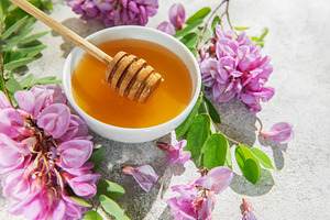 Acacia honey in bowl with honey dipper and flowers, a Food & Drink Photo by Olena Rudo