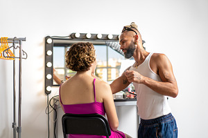 Professional male make-up artist applying makeup on woman in studio, a Person Photo by andreonegin market