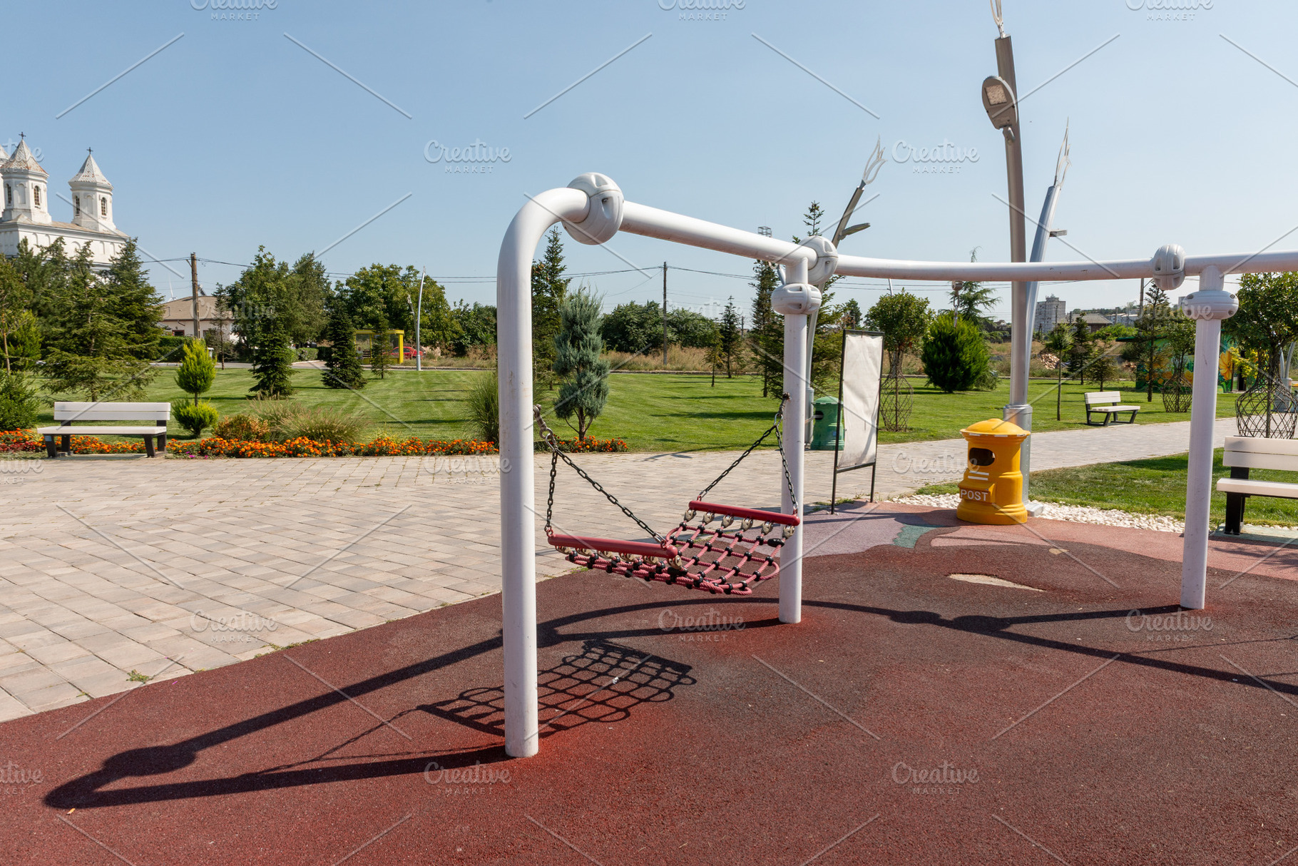 Contemporary swing set in a landscaped park with benches, greenery, and open sk, a Sports & Recreation Photo by Ales Munt