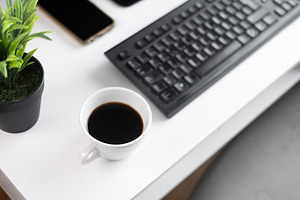 Black Coffee Cup on Minimal White Desk with Keyboard and Plant, a Business Photo by etorres69