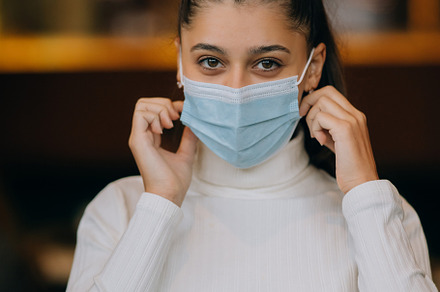 Girl in takes off her protective medical face mask