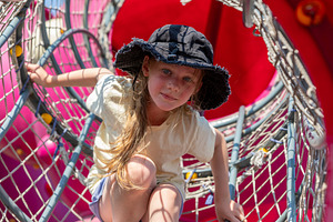Young girl in sun hat crawling through a net tunnel on a colorful playground, e, a Person Photo by Ales Munt