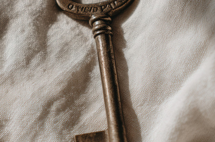 Vintage key on white linen, a Photo by Virgo Studio