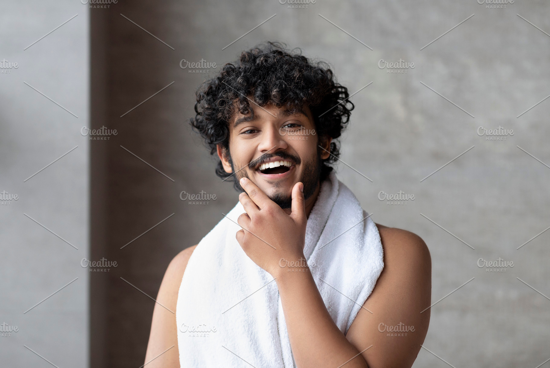 Portrait of happy bearded indian man with towel posing in bathroom and touching, a Person Photo by Prostock-Studio