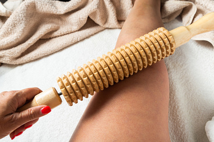 Hand holding a wooden massage roller during maderotherapy on the