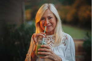 Smiling senior woman drinking green, a Person Photo by HalfPoint