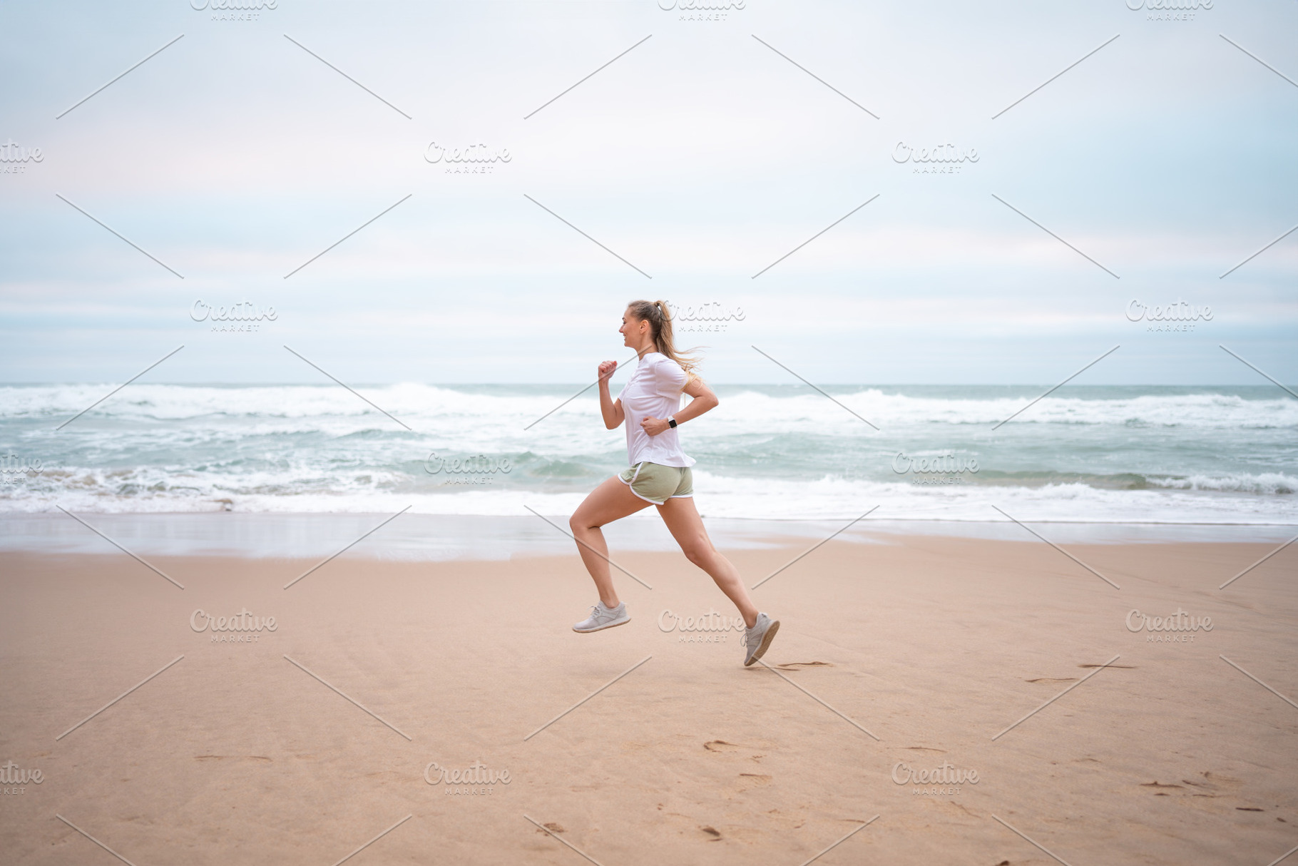 Determined sporty woman running on seashore at beach against sky, a Photo by andreonegin market