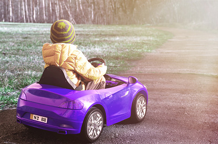 The boy is driving a blue car.