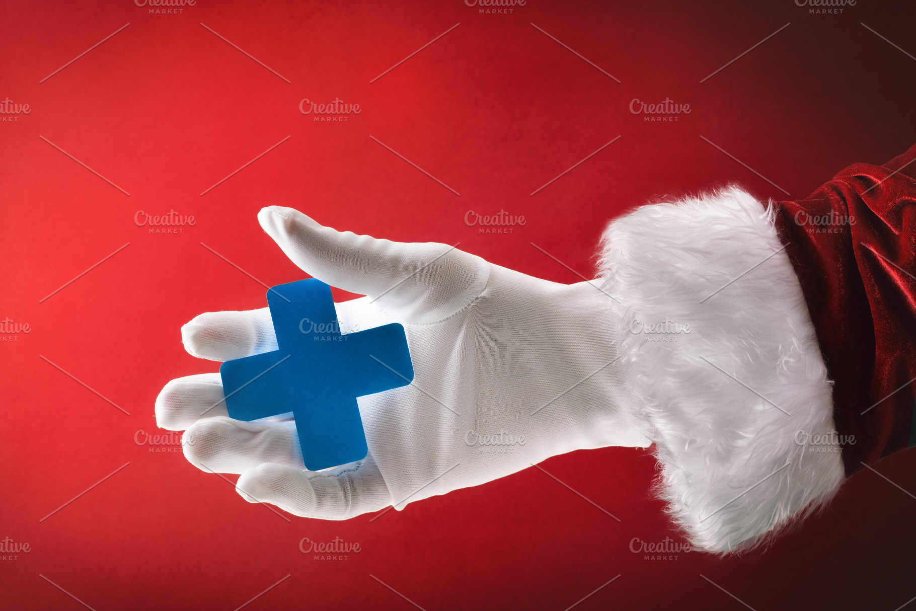 Santa Claus hand holding health cross on snowing blue background, a Holiday Photo by Davizro's Market