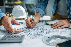 Architects reviewing blueprints plan, a Photo by Pixeness Studio