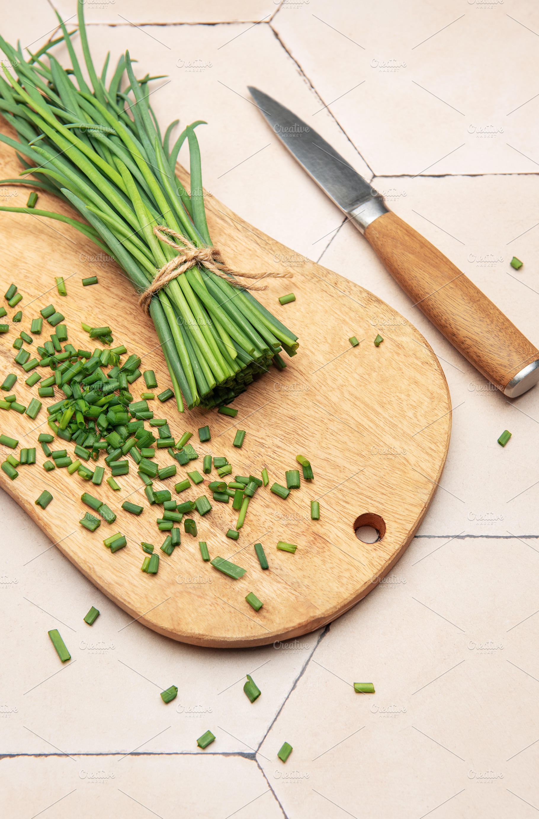 Freshly cut chives on wooden cutting board with knife, a Food & Drink Photo by Olena Rudo