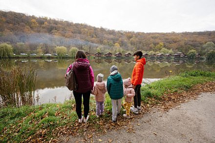 Back of mother with kids against wooden houses with smoke on the, a Person Photo by AS photostudio
