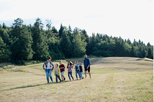 Young students walking across meadow, a Person Photo by HalfPoint