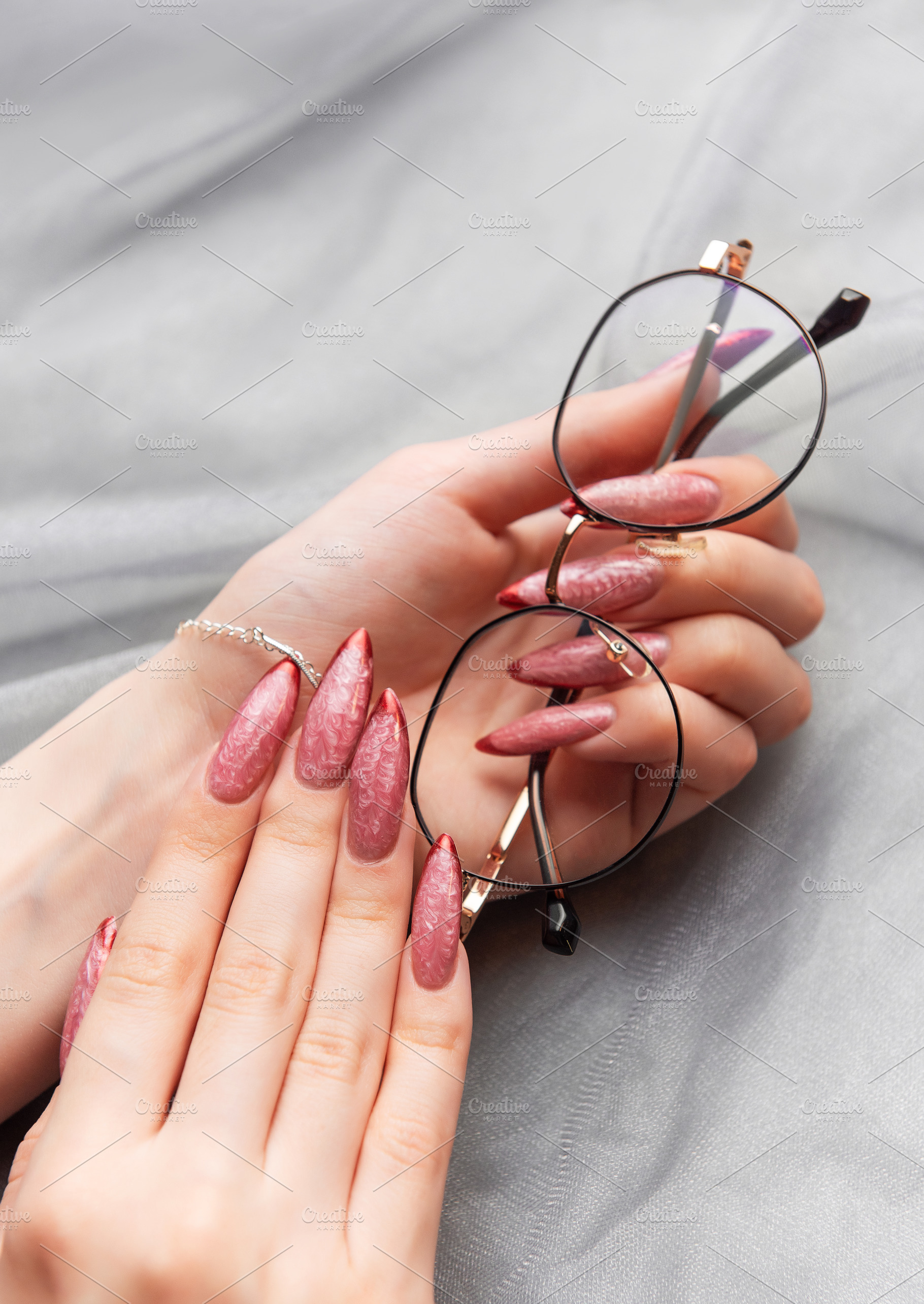 Feminine hands holding eyeglasses with stylish pink manicure, a Beauty & Fashion Photo by Olena Rudo