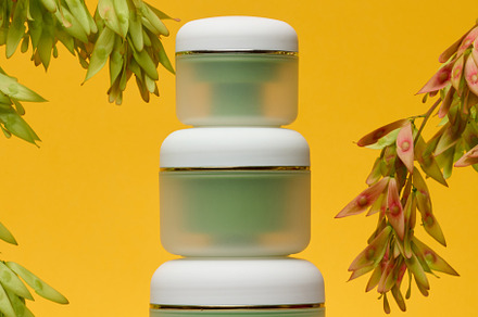 Matte green cosmetic jars with white lids, located on a white su