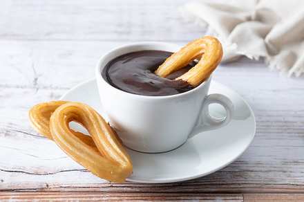 Traditional Spanish churros with hot chocolate breakfast on wooden table, a Food & Drink Photo by etorres69