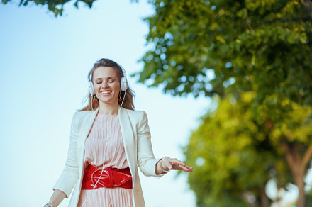 smiling trendy woman in city listening to music, a Person Photo by Alliance Images