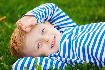Little boy lying on the grass containing green, grass, and boy