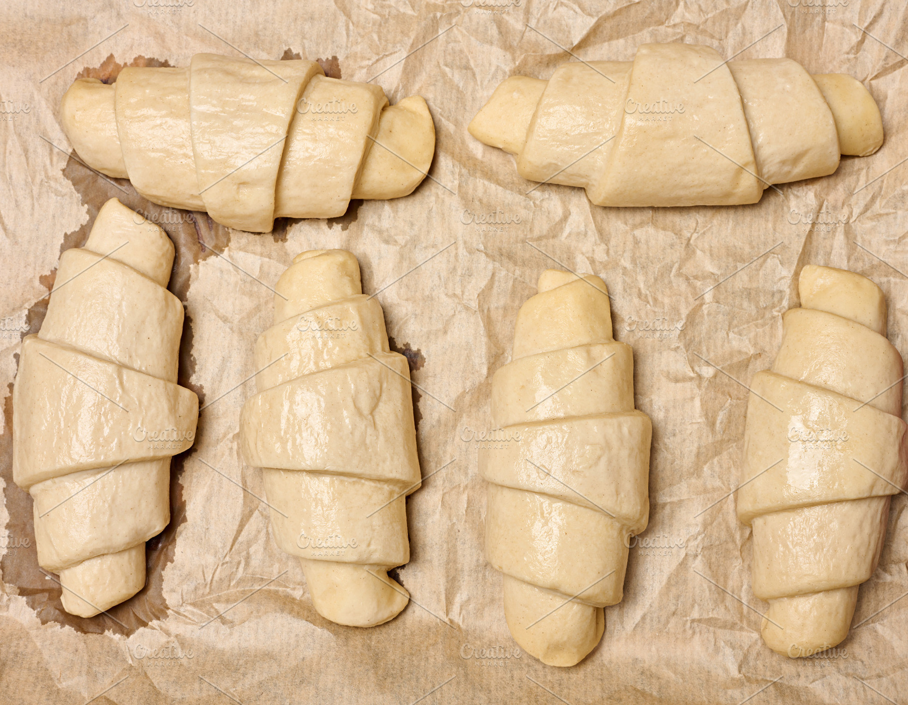 Uncooked croissant blanks on parchment paper, a Food & Drink Photo by ndanko