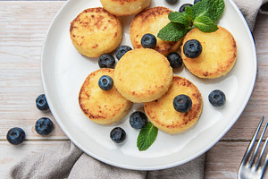 Golden syrniki cottage cheese pancakes with fresh blueberries, a Food & Drink Photo by Olena Rudo