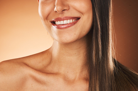 Happy, smile and woman with hair care, skincare and beauty cosmetic treatment in a studio. Happiness, health and girl model with a wellness facial skin routine isolated by a gradient brown background, a Photo by Peopleimages.com