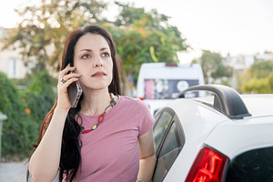 Woman standing by a white car, looking focused while talking on, a Person Photo by Imaginarium
