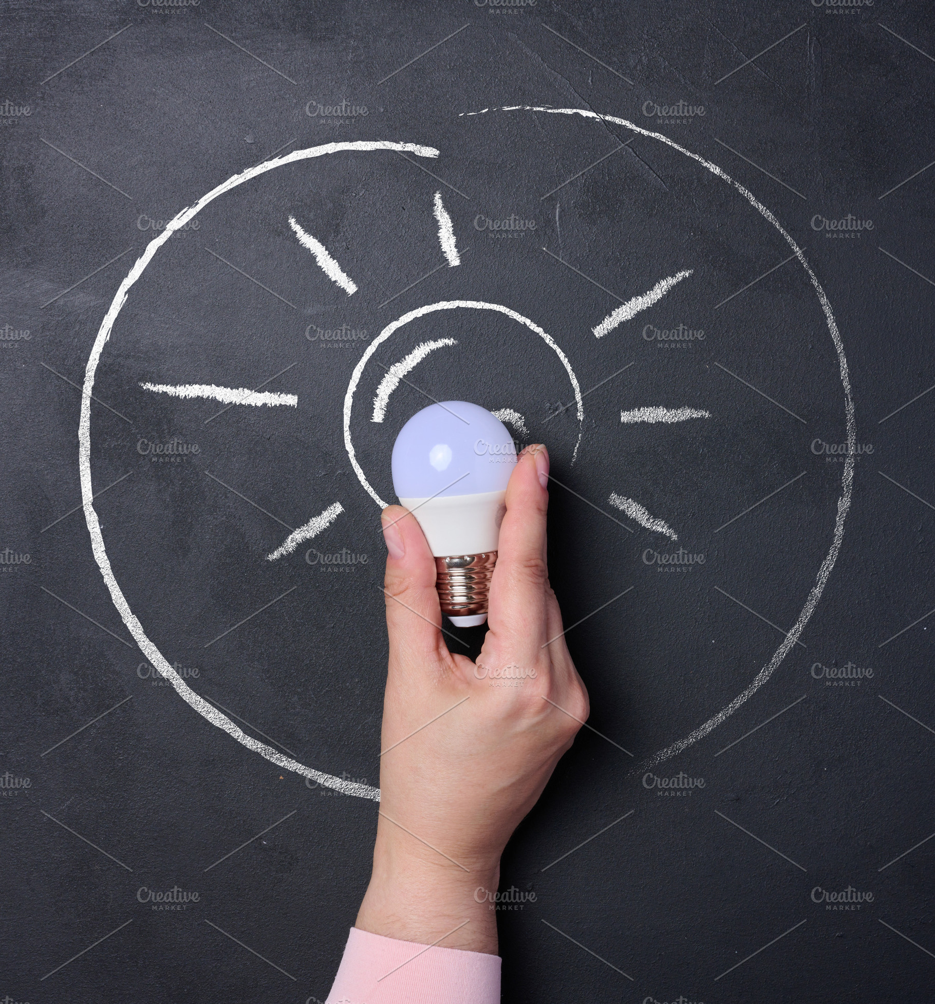 A human hand holding a light bulb, a chalk outline of the bulb w, a Business Photo by ndanko
