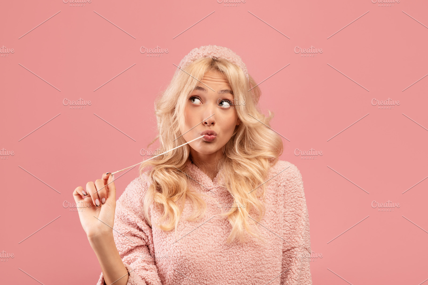 Pretty blonde woman stretching chewing gum from mouth and looking away at free, a Photo by Prostock-Studio