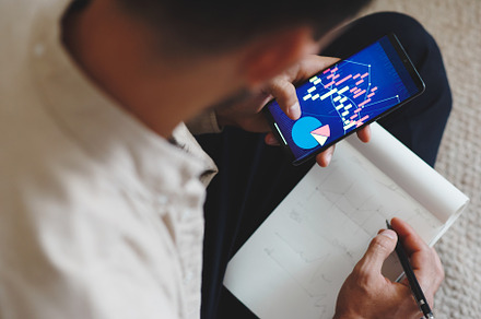 Man holding smartphone with graphs