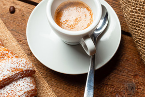 Steaming cup of espresso with croissant and coffee beans on wooden table, a Food & Drink Photo by Antonio Gravante Market