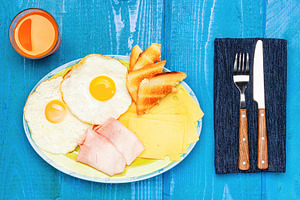 Energizing breakfast with fried eggs, ham, cheese and orange juice on blue wood, a Food & Drink Photo by Antonio Gravante Market