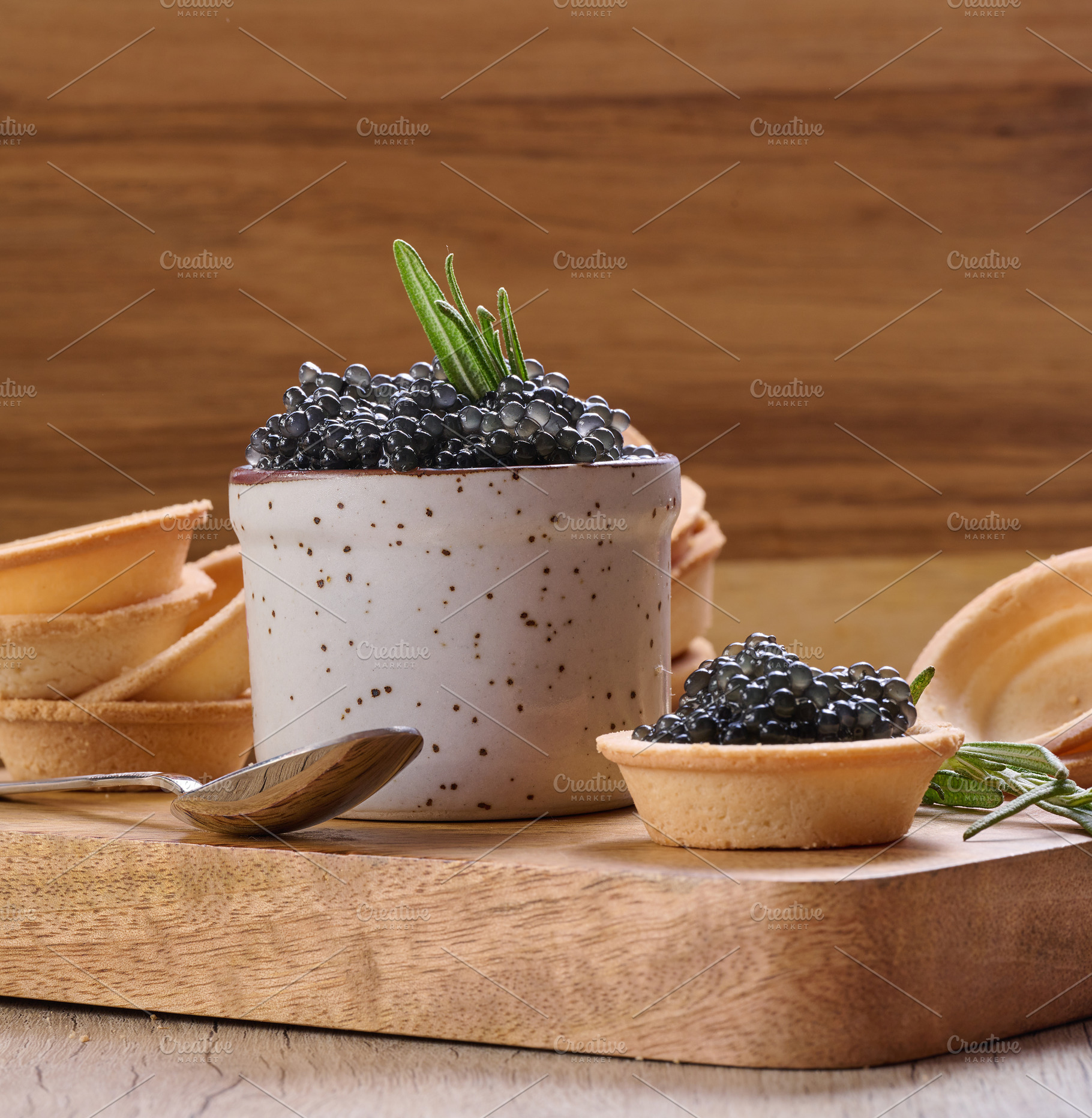 Black caviar in mini tartlet on wooden board, ceramic pot with c, a Food & Drink Photo by ndanko