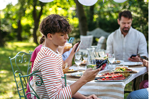 Boy looking at phone during family, a Person Photo by HalfPoint