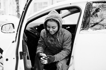 African american woman in red hoodie sitting inside car at winte, a Person Photo by AS photostudio